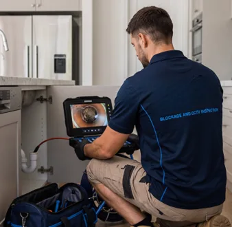 Plumber clearing a blocked toilet in a Paddington bathroom